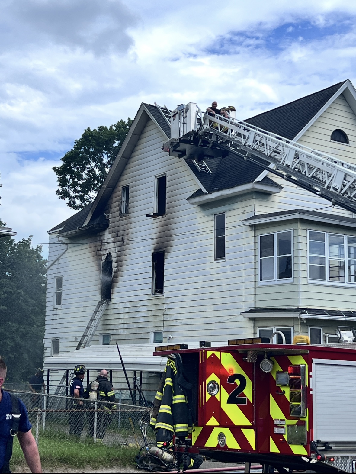 Active fire scene with firefighters on aerial ladder